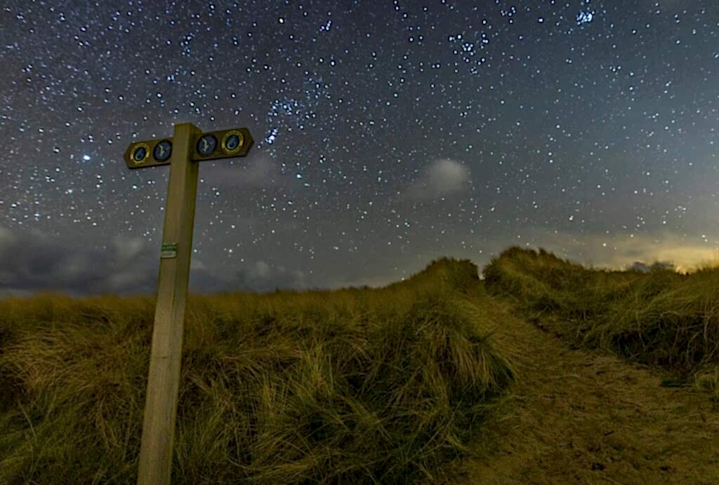 A sign on the dunes at night