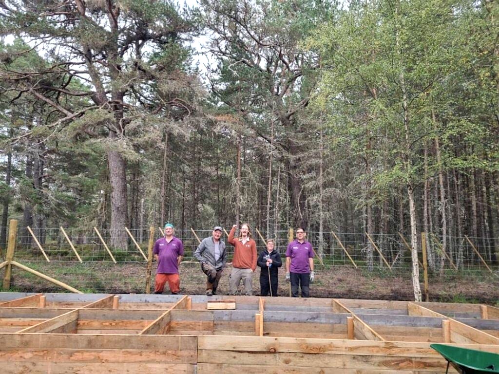 A group of people stand behind newly built plant beds for the Twinflower nursery in the Cairngorms, Scotland